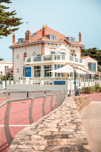 a large building with a tennis court in front of it at Hôtel de charme & SPA Le Grand Large in La Bernerie-en-Retz