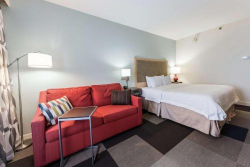 a hotel room with a bed and a red couch at Hampton Inn Columbus I-70E/Hamilton Road in Columbus