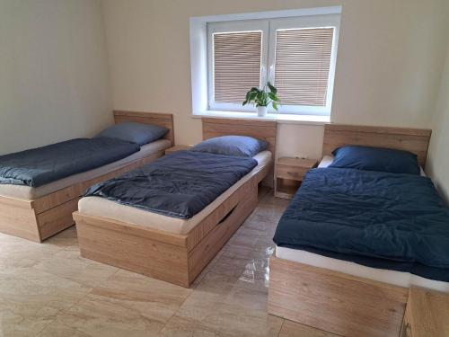 three beds in a room with a window at Penzion FRENAT in Kúty