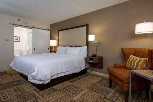 a hotel room with a bed and a chair at Hampton Inn Commerce in Commerce