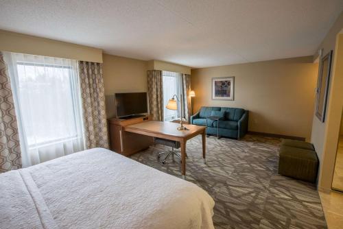 Cette chambre comprend un lit, un bureau et un canapé. dans l'établissement Hampton Inn & Suites Tilton, à Tilton
