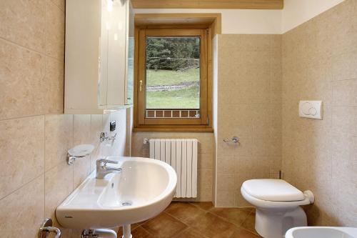een badkamer met een wastafel, een toilet en een raam bij Casa Michela Bilocale in Valfurva