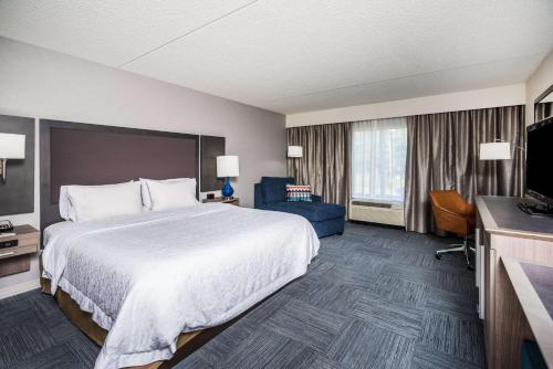 a hotel room with a large bed and a flat screen tv at Hampton Inn Clifton Park in Clifton Park