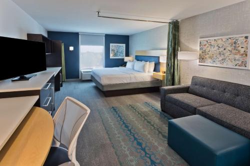 Home2 Suites by Hilton Columbus في كولومبوس: غرفه فندقيه بسرير واريكه