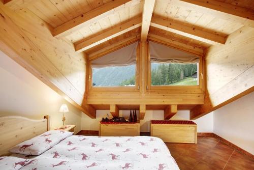 een slaapkamer met een bed en een groot raam bij Casa Michela Mansarda in Valfurva