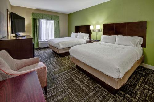 a hotel room with two beds and a chair at Hampton Inn Crossville in Crossville