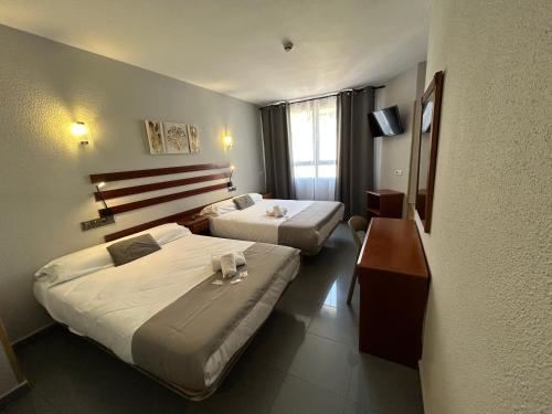 a hotel room with two beds and a desk at Hotel Valdemoro in Valdemoro
