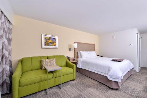 Habitación de hotel con cama y sofá verde en Hampton Inn Cartersville, en Cartersville