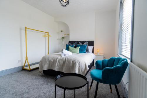 a bedroom with a bed and a blue chair at Stylish 3 Bedroom House - Central Location in Nottingham