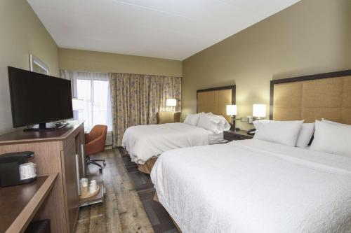 a hotel room with two beds and a flat screen tv at Hampton Inn Cincinnati Eastgate in Eastgate