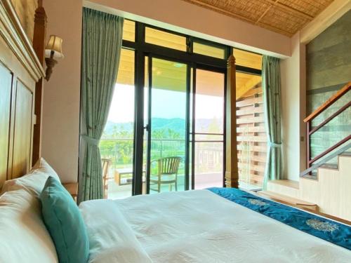 um quarto com uma cama e uma grande janela em Roaming Cloud Sun Moon Lake B&B em Yuchi