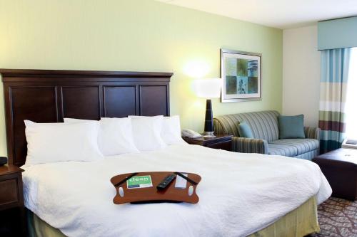 フェアフィールドにあるHampton Inn Cincinnati Northwest Fairfieldのトレイ付きのベッドが備わるホテルルームです。