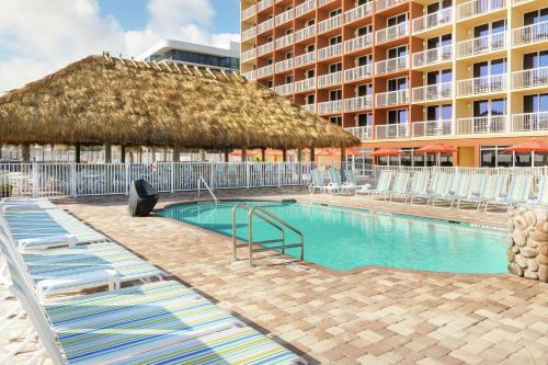 a swimming pool with chairs and a large building at Hampton Inn Daytona Beach/Beachfront in Daytona Beach