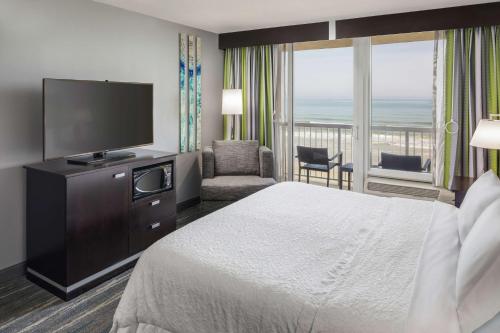 Hampton Inn Daytona Beach/Beachfront في دايتونا بيتش: غرفة فندقية بسرير وتلفزيون بشاشة مسطحة