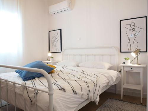 a white bedroom with a white bed and two pictures on the wall at Breeze 1BD Apartment by BluPine in Athens