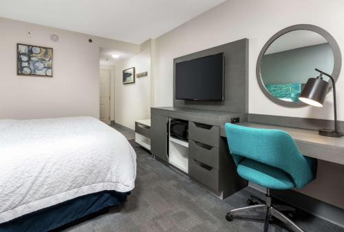 a bedroom with a bed and a desk with a television at Hampton Inn Daytona Shores-Oceanfront in Daytona Beach