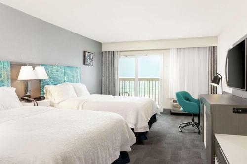 デイトナビーチにあるHampton Inn Daytona Shores-Oceanfrontのベッド2台、薄型テレビが備わるホテルルームです。
