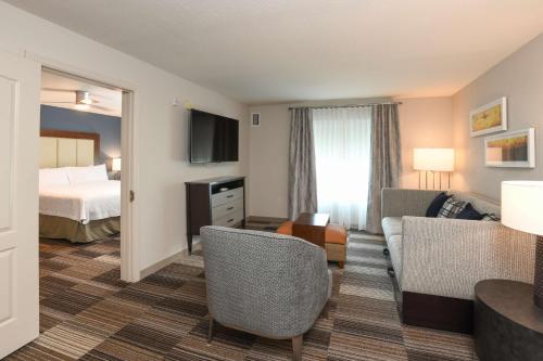 a hotel room with a bed and a living room at Homewood Suites Cincinnati Airport South-Florence in Florence