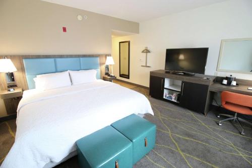 a hotel room with a bed and a desk and a television at Hampton Inn & Suites Palm Coast in Flagler Beach