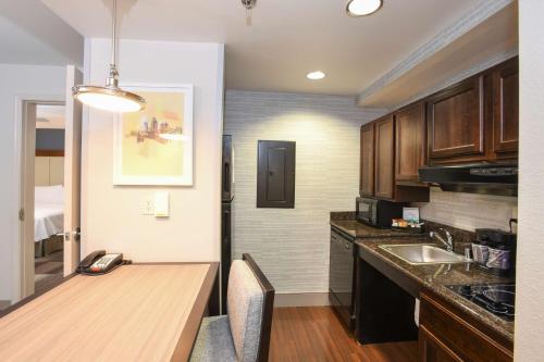 a kitchen with a wooden table and a sink at Homewood Suites Cincinnati Airport South-Florence in Florence