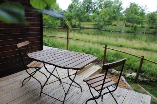 a picnic table and two chairs on a wooden deck at LES GRANGES D'ANTAN - le REFUGE FORESTIER - INSOLITE SANS EAU - ELECTRICITE AVEC BATTERIE NOMADE in Chalonnes-sous-le-Lude