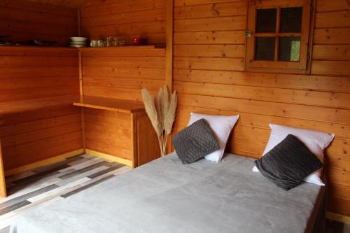 a room with a bed in a log cabin at LES GRANGES D'ANTAN - le REFUGE FORESTIER - INSOLITE SANS EAU - ELECTRICITE AVEC BATTERIE NOMADE in Chalonnes-sous-le-Lude