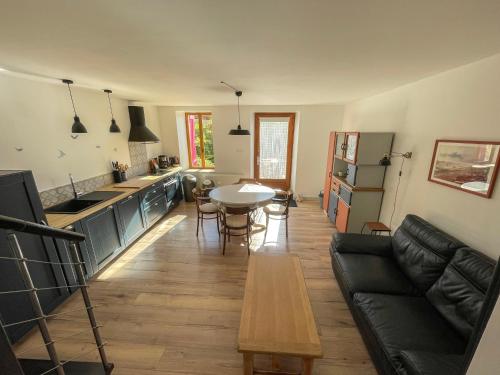 cocina y sala de estar con sofá y mesa en Ferme Robin, en Marsaz