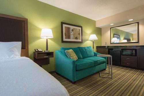 a hotel room with a bed and a blue couch at Hampton Inn Brooksville Dade City in Ridge Manor