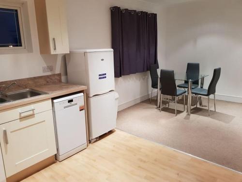 een keuken met witte apparatuur en een tafel en stoelen bij Guest Homes - Propelair Apartment in Colchester