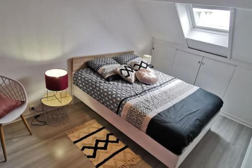 um quarto com uma cama com almofadas e uma janela em Appartement cosy, 300m de la mer em Donville-les-Bains