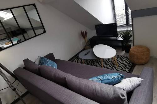 uma sala de estar com um sofá e uma mesa em Appartement cosy, 300m de la mer em Donville-les-Bains