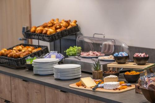 EstillacにあるThe Originals City, Relais d'Estillac, Agen Sudのテーブルの上に皿と食べ物を並べたビュッフェ