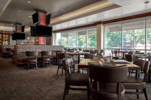 a restaurant with tables and chairs and windows at DoubleTree by Hilton Hotel Dallas - Love Field in Dallas