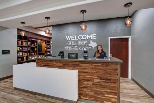 a woman standing at a welcome counter in a store at Hampton Inn & Suites Dallas-DeSoto in DeSoto