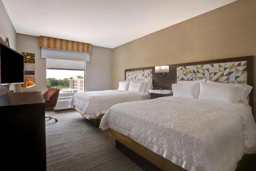 a hotel room with two beds and a flat screen tv at Hampton Inn & Suites Dallas-DeSoto in DeSoto