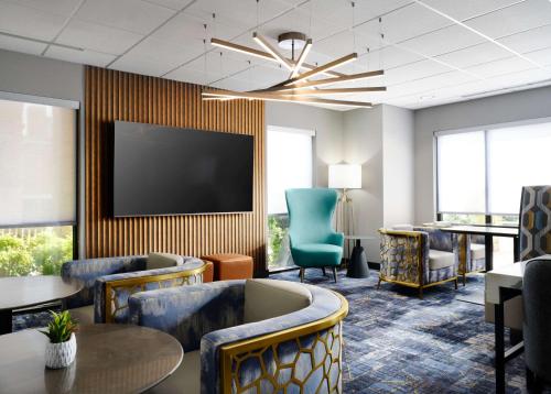 una sala d'attesa con sedie, tavoli e TV a schermo piatto di Hampton Inn & Suites Dallas-DFW Airport Hurst a Hurst