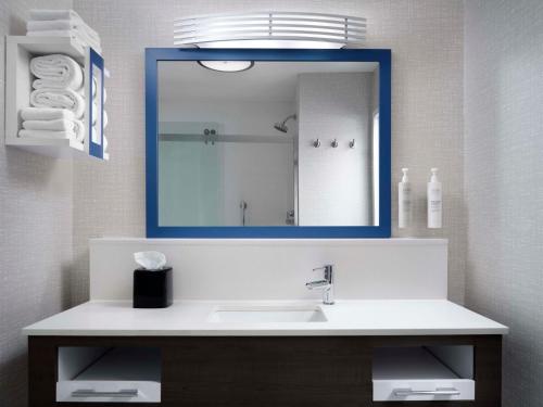 a bathroom with a sink and a blue mirror at Hampton Inn & Suites Dallas-DFW Airport Hurst in Hurst