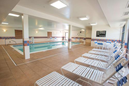 a swimming pool with white chairs next to a swimming pool at Hampton Inn & Suites Dayton-Airport in Englewood