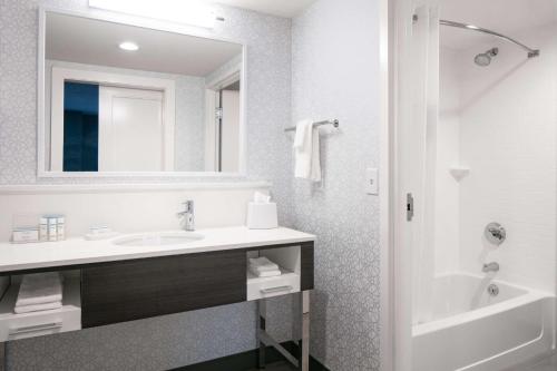 a bathroom with a sink and a tub and a mirror at Hampton Inn Dubuque in Dubuque