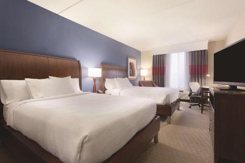 a hotel room with two beds and a flat screen tv at Hilton Garden Inn Falls Church in Falls Church