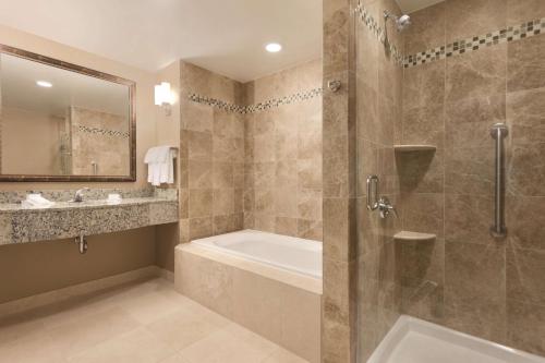y baño con ducha, bañera y lavamanos. en Hilton Garden Inn Falls Church en Falls Church