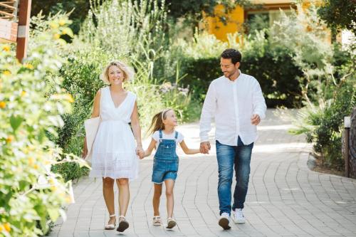 a family walking through a garden holding hands at Canado Club Family Village in Marina di Castagneto Carducci