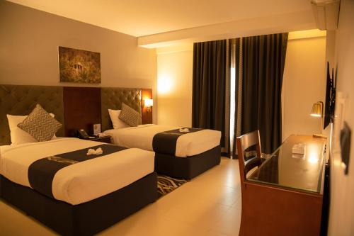 塞拉莱Tulip Inn Majan Hotel and Suites Salalah的有两张床和一扇窗户的酒店房间