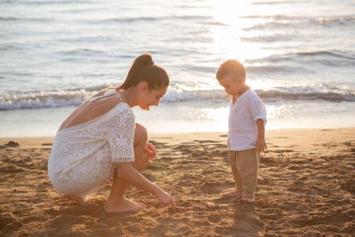 a woman and a child playing in the sand on the beach at Canado Club Family Village in Marina di Castagneto Carducci