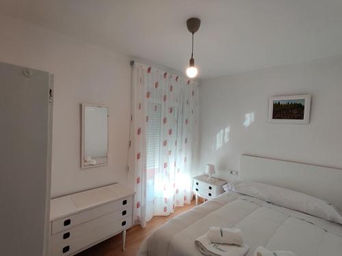 a white bedroom with a bed and a mirror at Casa El Carmen in Alar del Rey