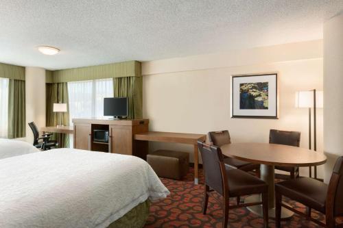 a hotel room with a bed and a table and chairs at Hampton Inn Denver West Federal Center in Lakewood
