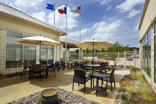 a patio with tables and chairs and umbrellas at Hilton Garden Inn Dallas Arlington in Arlington