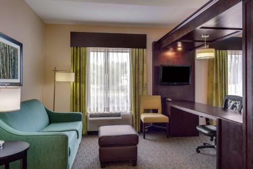 a hotel room with a couch and a chair and a desk at Hampton Inn Ozark in Ozark
