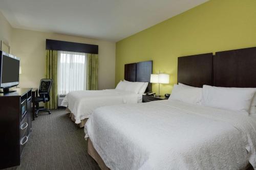 a hotel room with two beds and a flat screen tv at Hampton Inn Ozark in Ozark