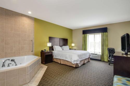 a hotel room with a bed and a bath tub at Hampton Inn Ozark in Ozark